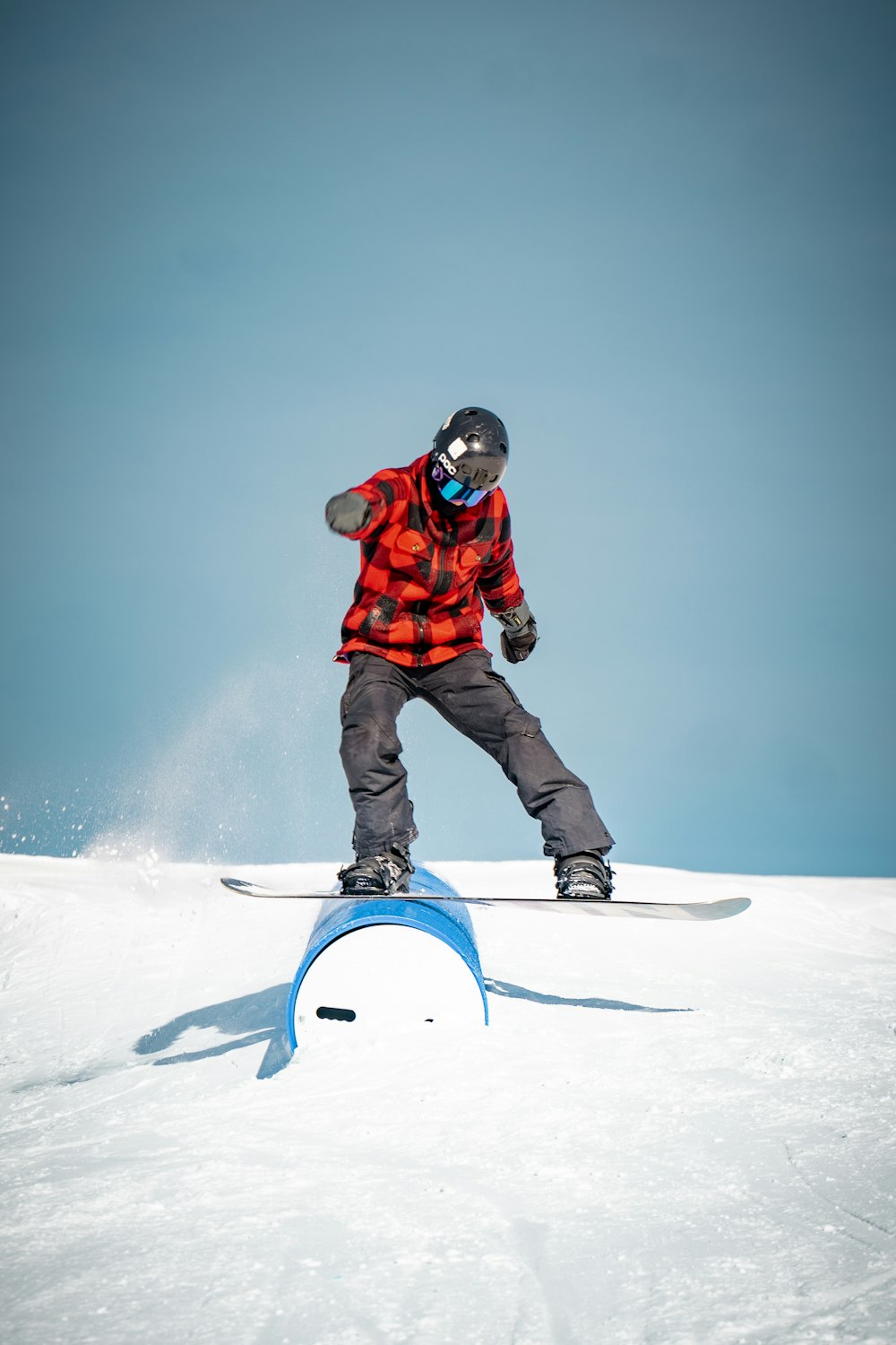 man in red jacket and black pants riding on snowboard