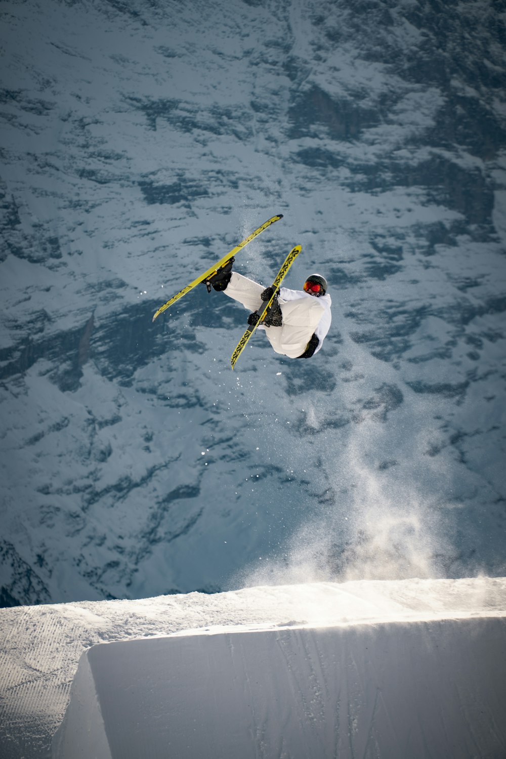 uomo in camicia bianca e pantaloni gialli che cavalcano su snowboard giallo e bianco su neve coperta