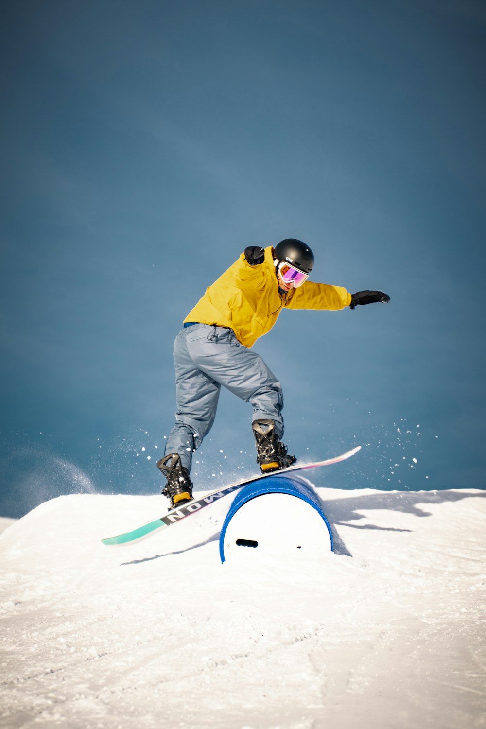 黄色いジャケットと灰色のズボンを着た男性が昼間、青いスノーボードに乗っている