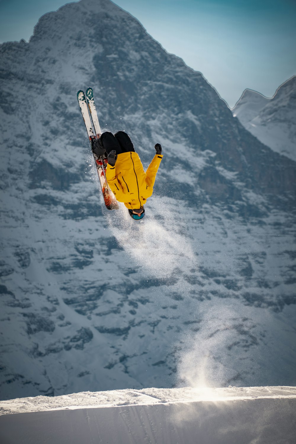 Mann in gelber Jacke und blauer Jeans fährt orangefarbenes Snowboard auf schneebedeckten Bergen während