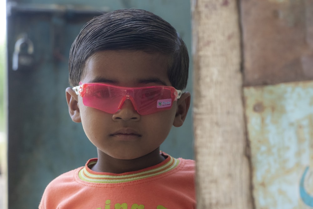 boy in red crew neck shirt wearing red framed sunglasses