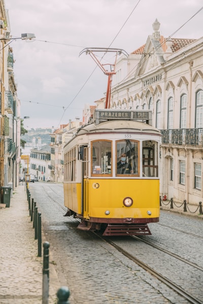 yellow and white tram on road near white concrete building during daytime