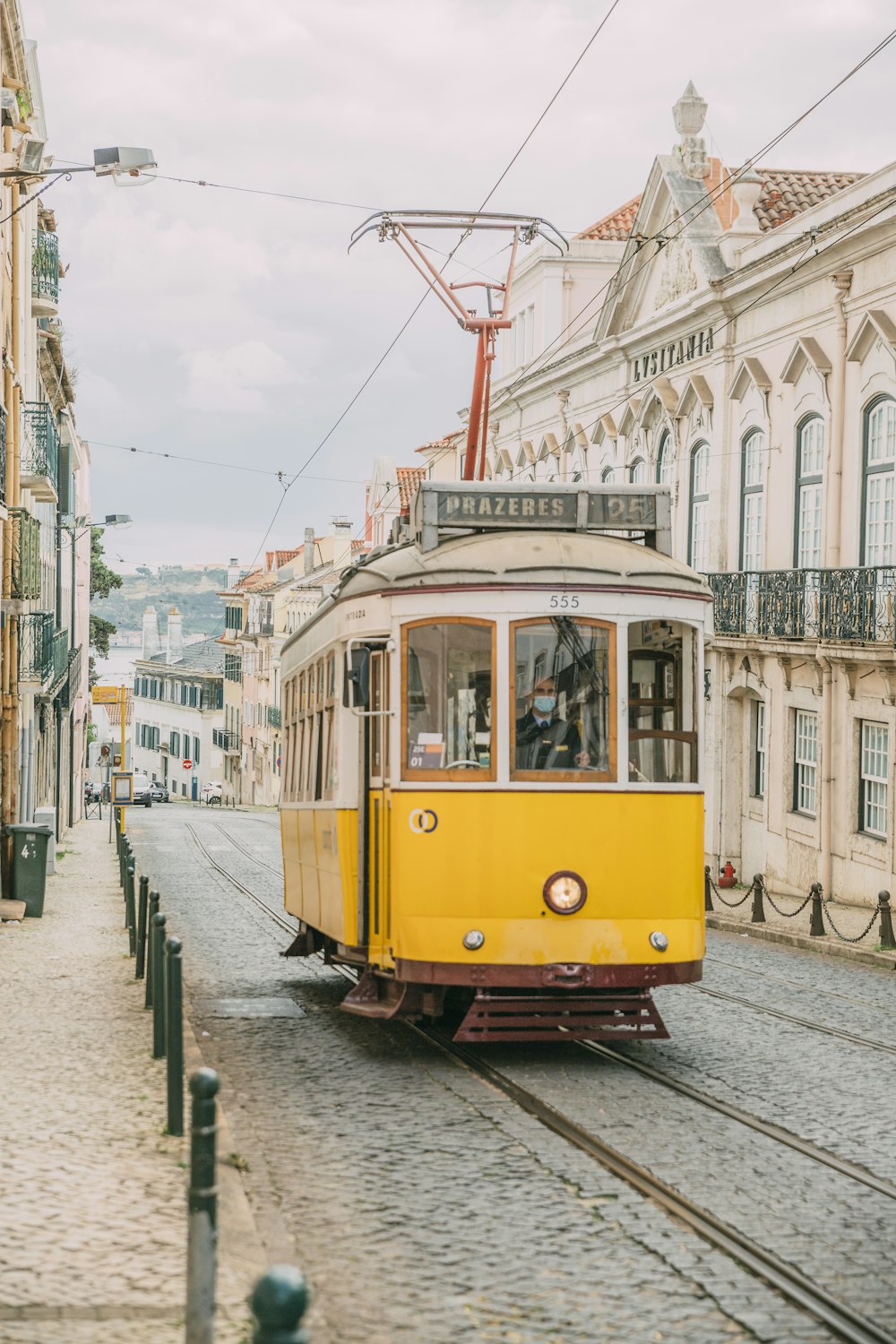 Tramway jaune et blanc sur la route près d’un bâtiment en béton blanc pendant la journée