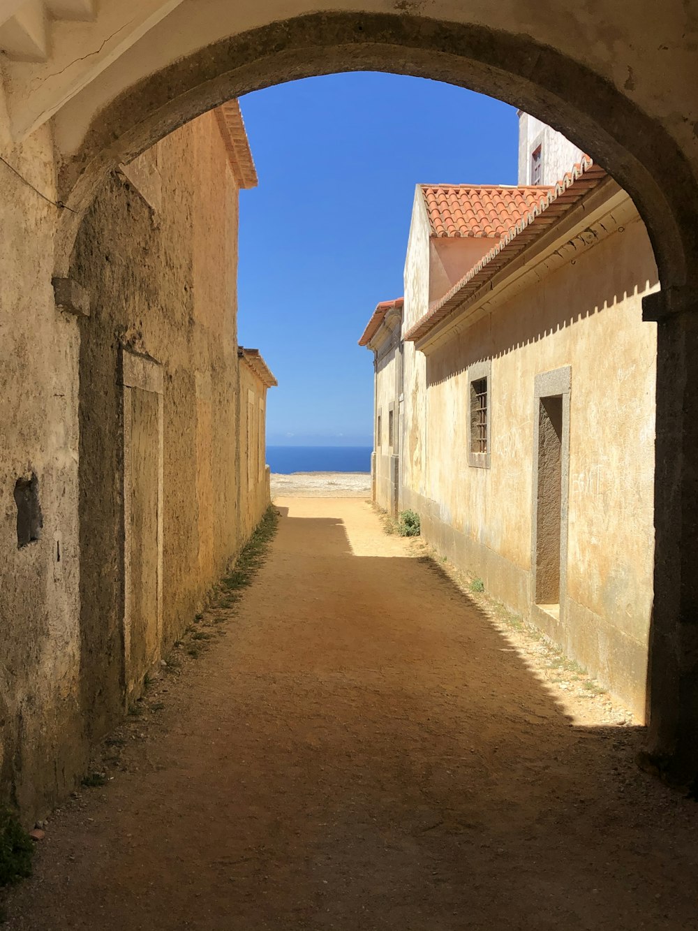 brown concrete pathway between white concrete buildings under blue sky during daytime