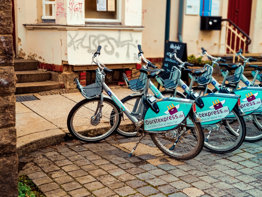 blue and black bicycle parked beside brown brick wall during daytime