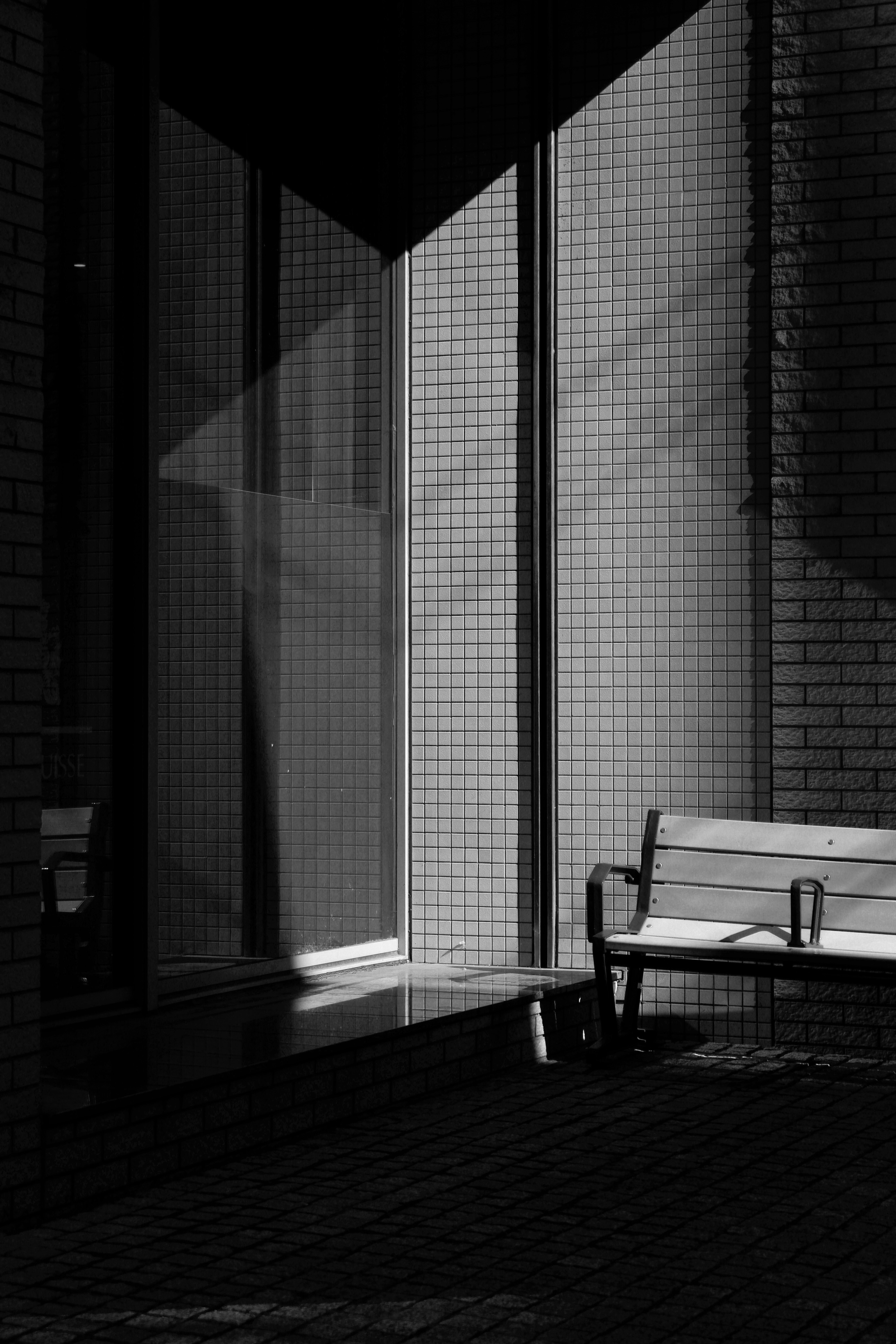 grayscale photo of bench near window