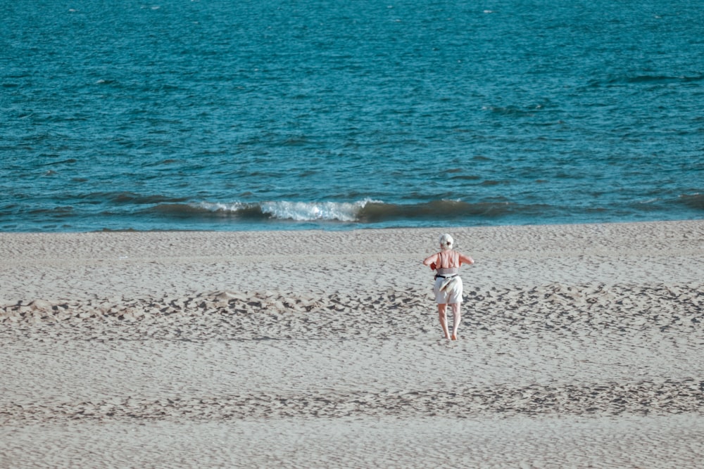 girl in white and red dress walking on beach during daytime