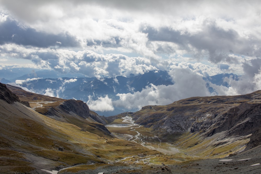 montanhas marrons e verdes sob nuvens brancas e céu azul durante o dia