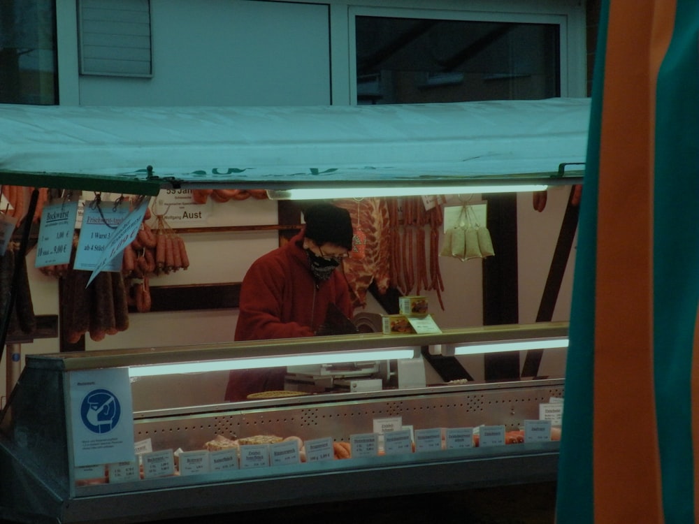 man in red polo shirt standing in front of store