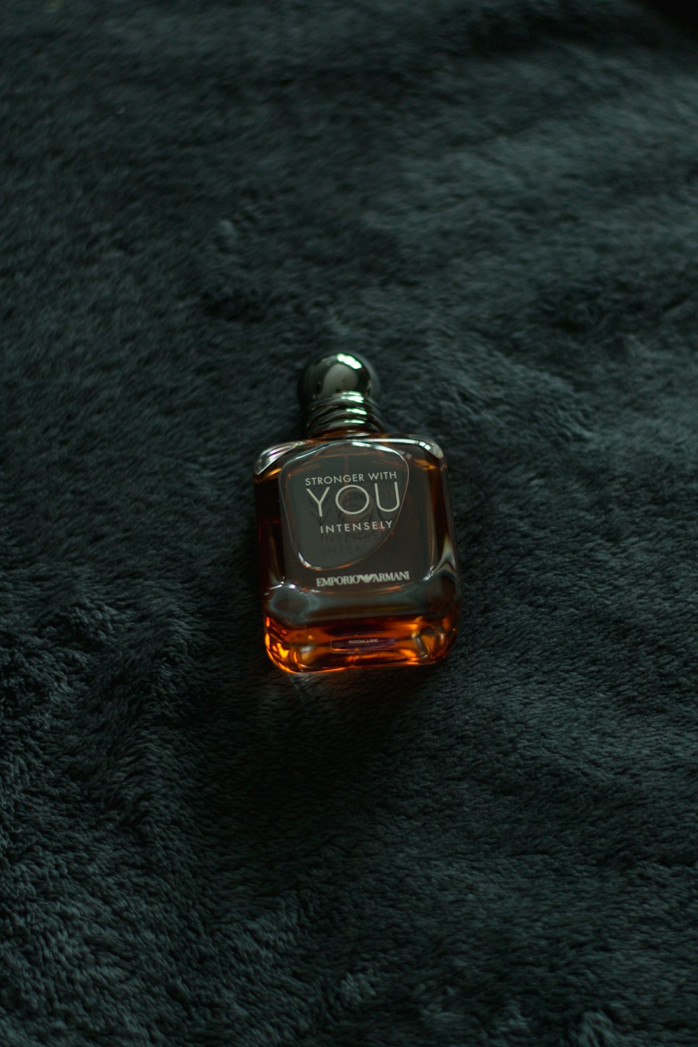 frasco de perfume preto e dourado no tecido preto