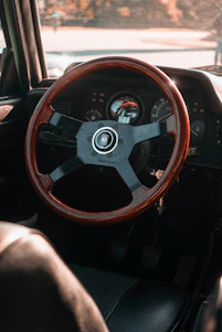 A close-up shot of a classic car's dashboard with vintage gauges and a steering wheel in warm sunlight.