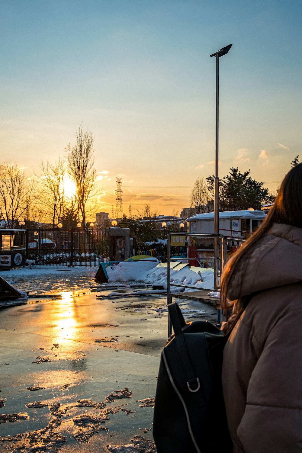 woman in brown jacket standing on snow covered ground during sunset