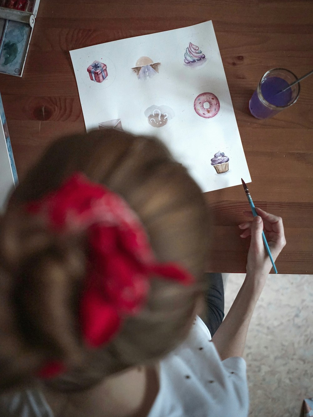 girl in white shirt holding pink and blue paint brush