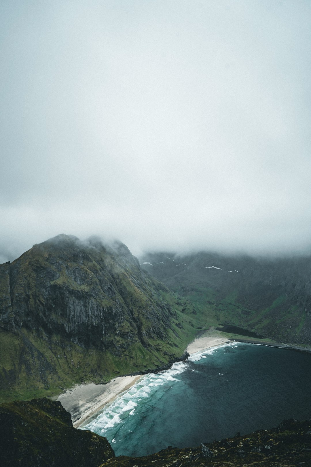 green mountain beside body of water