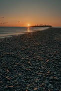 black and brown stones on beach during sunset
