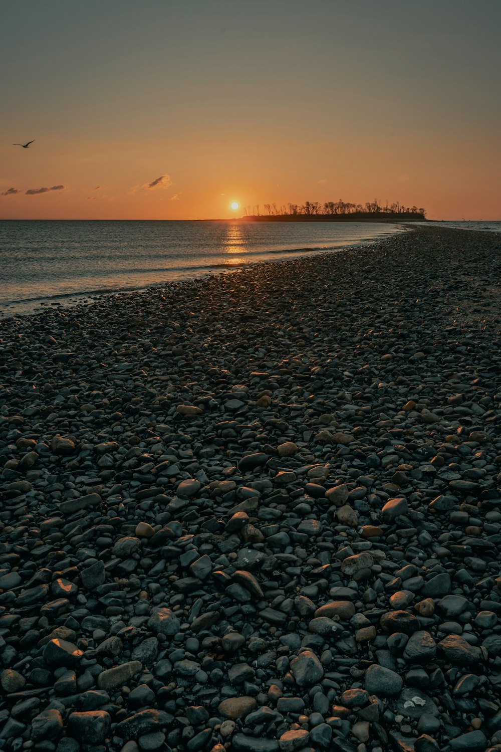 pedras pretas e marrons na praia durante o pôr do sol