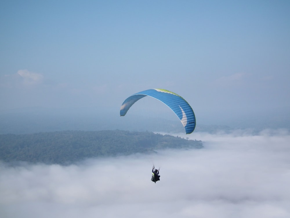 person in black jacket riding on blue parachute