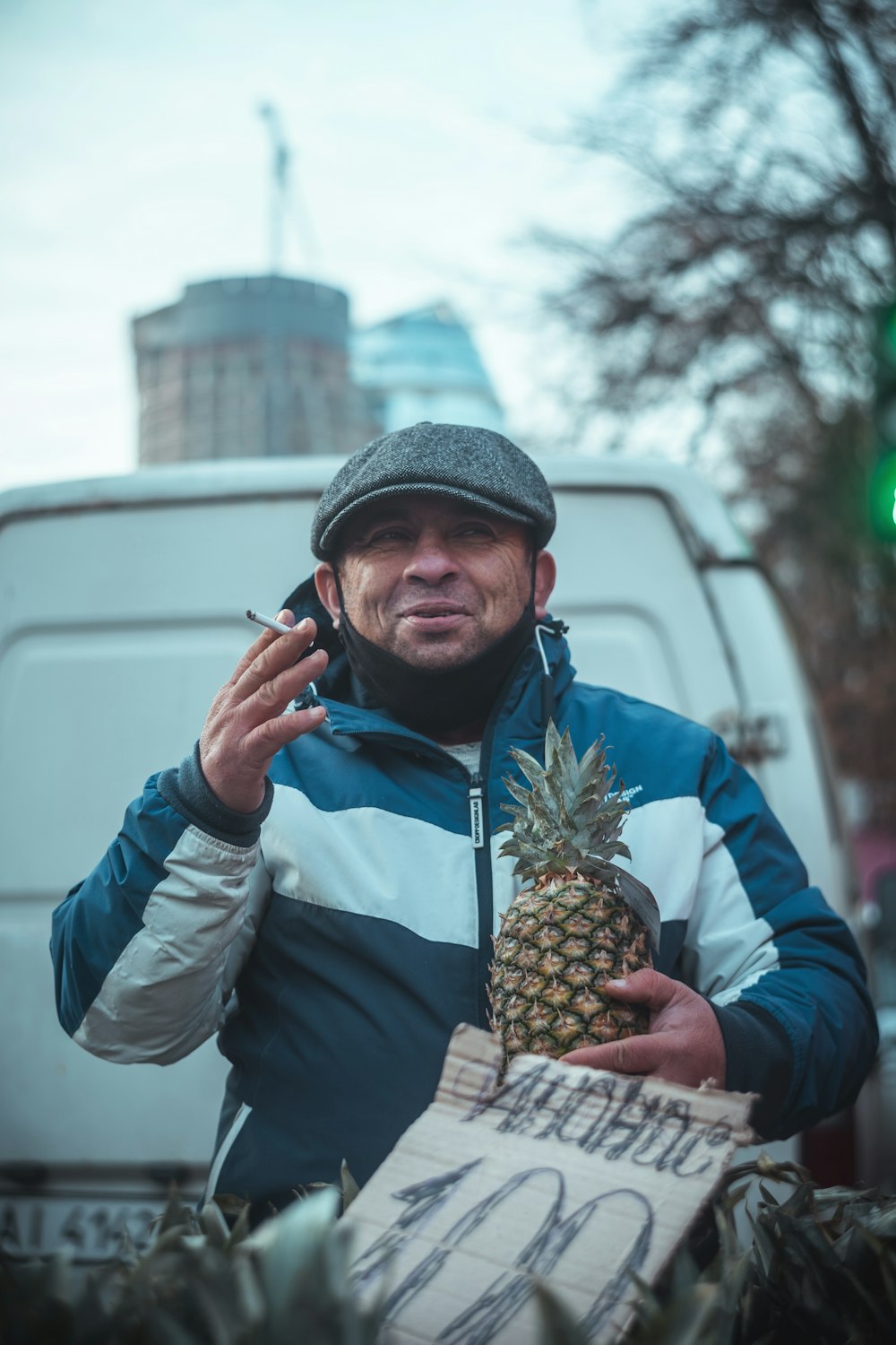 man in blue jacket and gray knit cap holding pineapple fruit