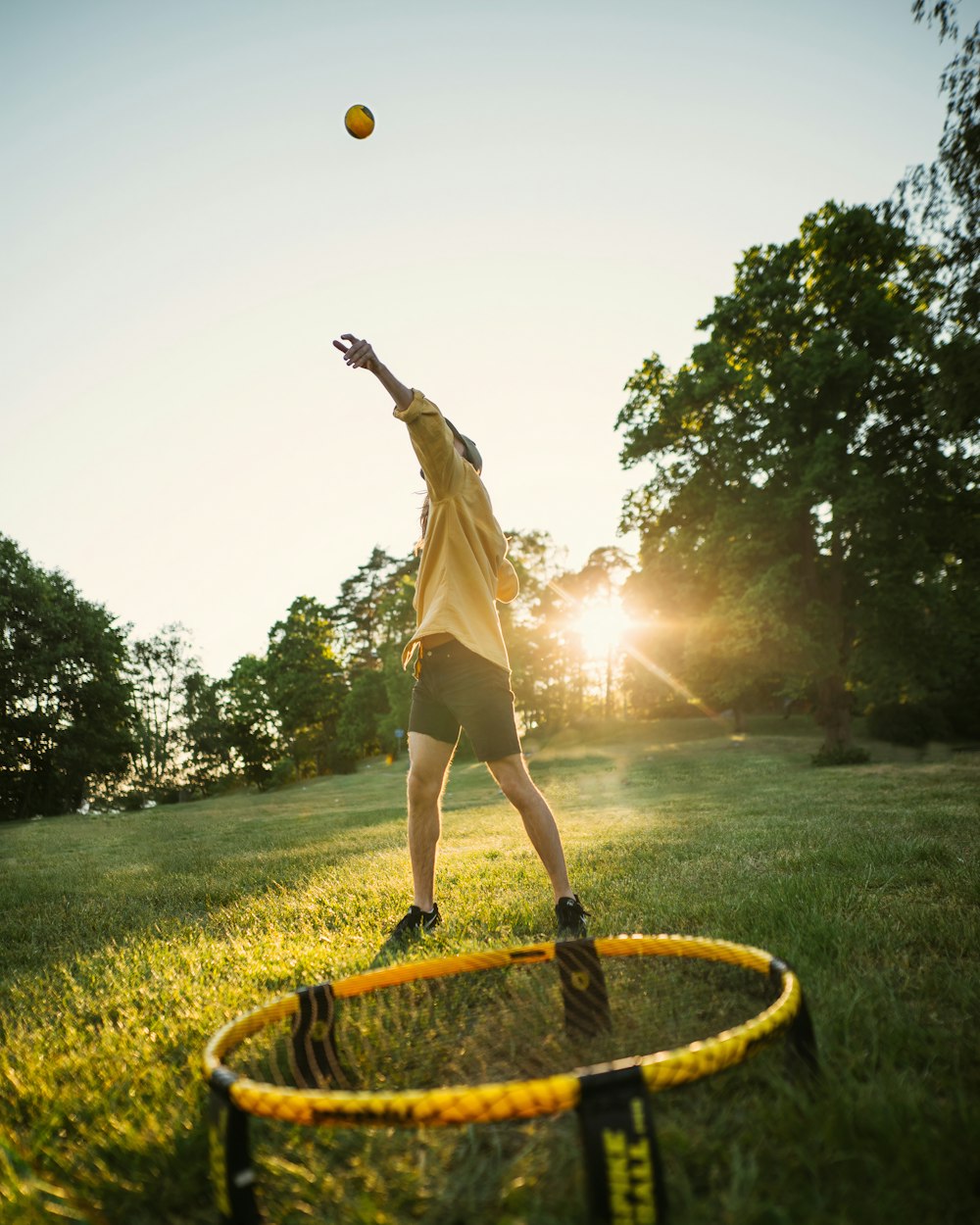 woman in white dress jumping on yellow round trampoline during daytime