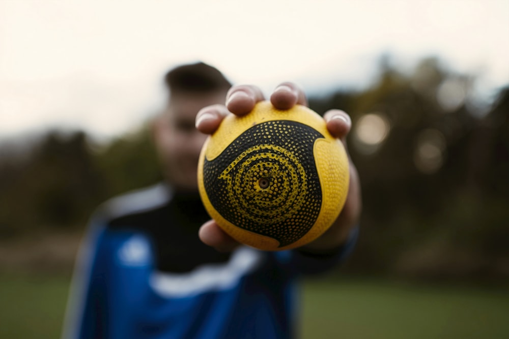 person holding yellow and black round speaker