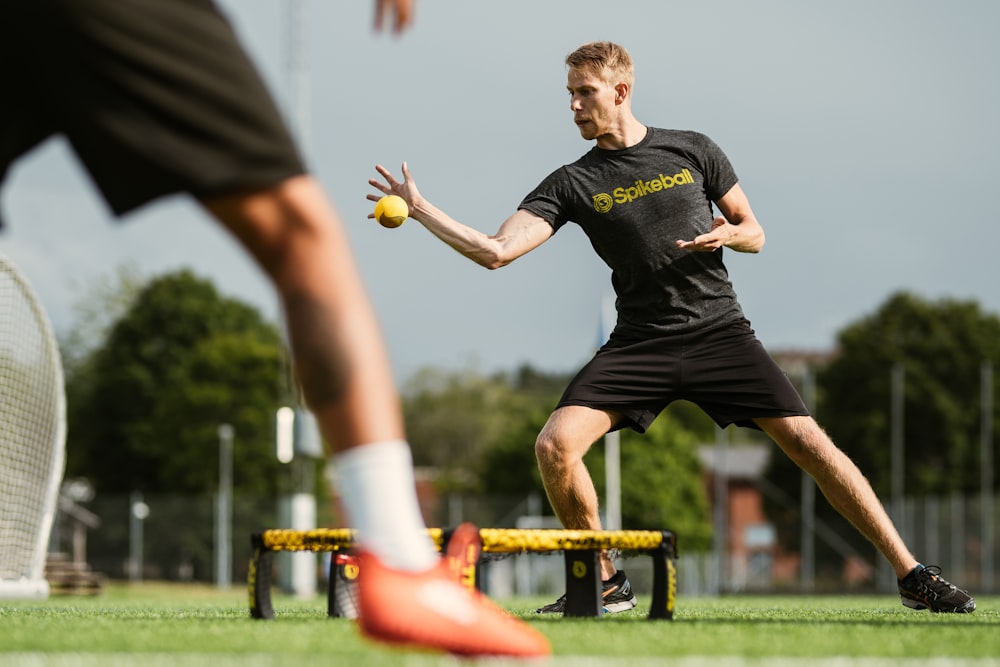 man in black crew neck t-shirt and black shorts playing soccer during daytime