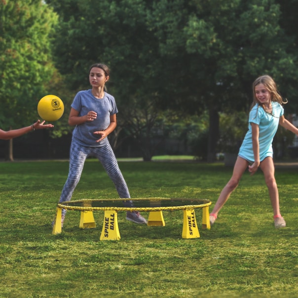 2 women playing soccer on green grass field during daytime