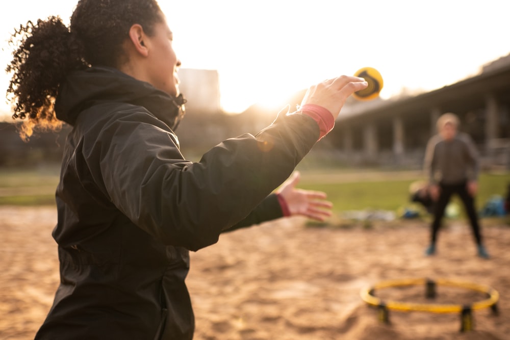 man in black jacket holding yellow ball during daytime