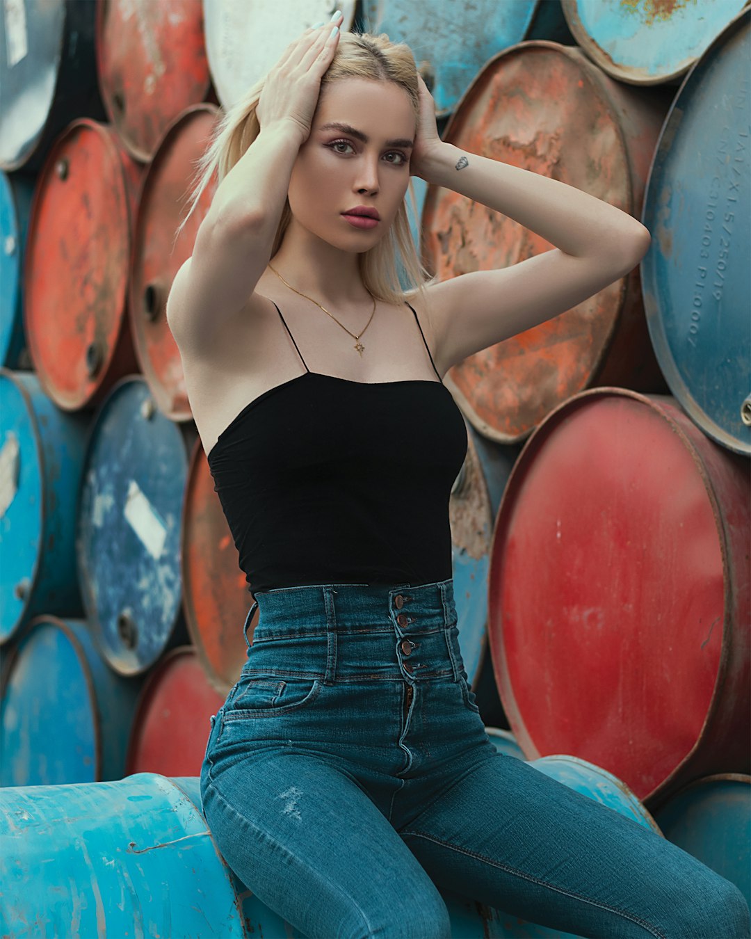 woman in black spaghetti strap top and blue denim jeans sitting on round drum