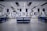 A spacious, modern warehouse or industrial interior with high ceilings and a sleek, organized layout. The space features several workstations equipped with monitors, barcode scanners, and storage areas. The setting is well-lit and appears clean and efficient, suggesting an environment designed for streamlined operations.