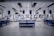 A spacious, modern warehouse or industrial interior with high ceilings and a sleek, organized layout. The space features several workstations equipped with monitors, barcode scanners, and storage areas. The setting is well-lit and appears clean and efficient, suggesting an environment designed for streamlined operations.