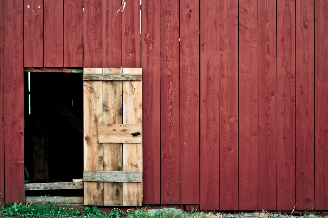 Single door opened on big red barn revealing the dark interior
