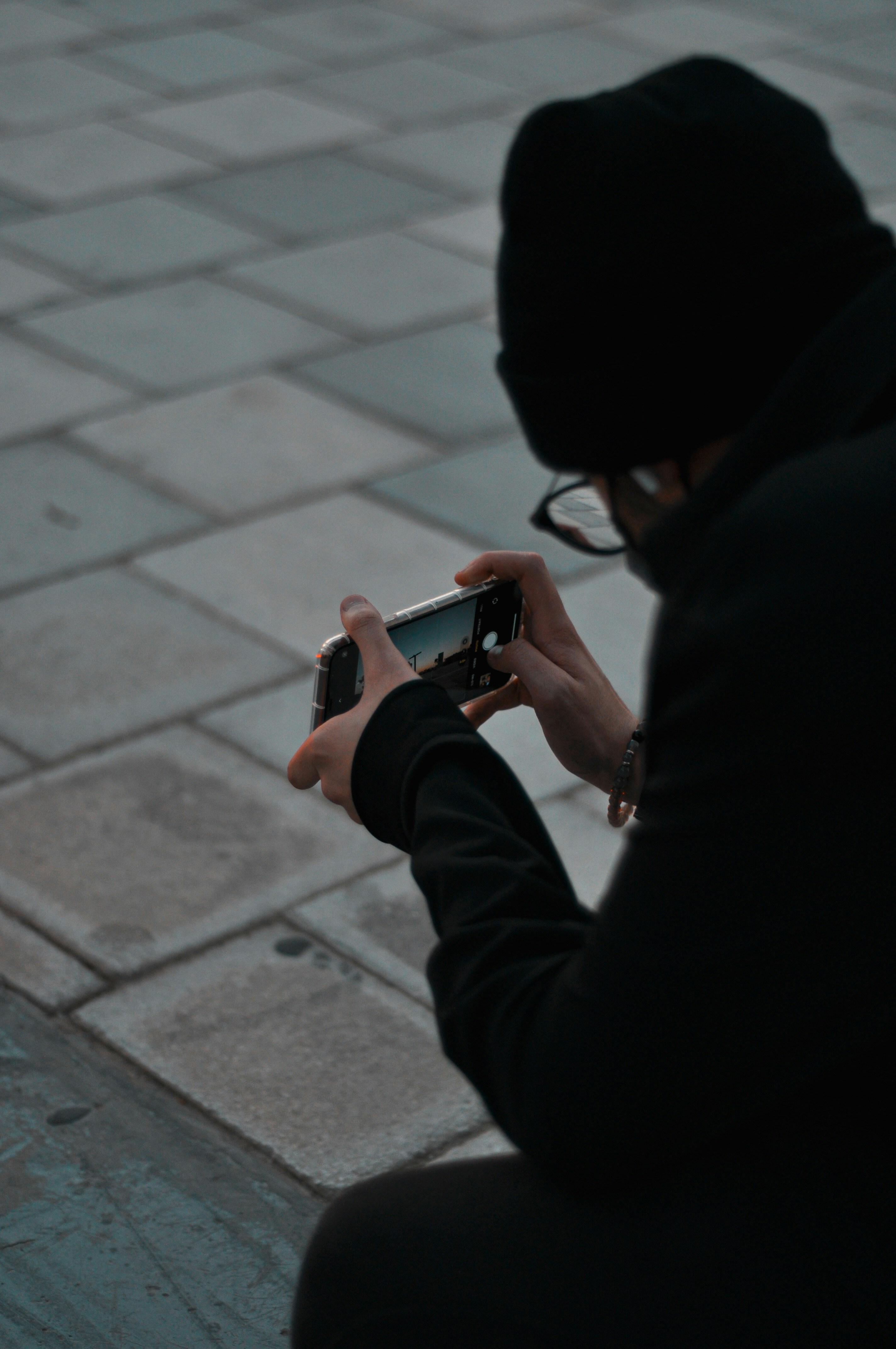 person in black jacket holding black smartphone