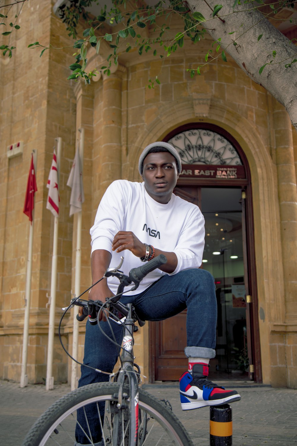 Hombre en camiseta blanca de cuello redondo y jeans de mezclilla azul sentado en bicicleta negra