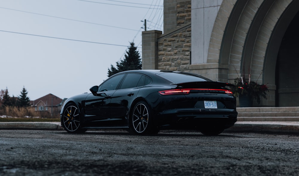 Schwarzer Porsche 911 parkt in der Nähe von brauner Ziegelmauer