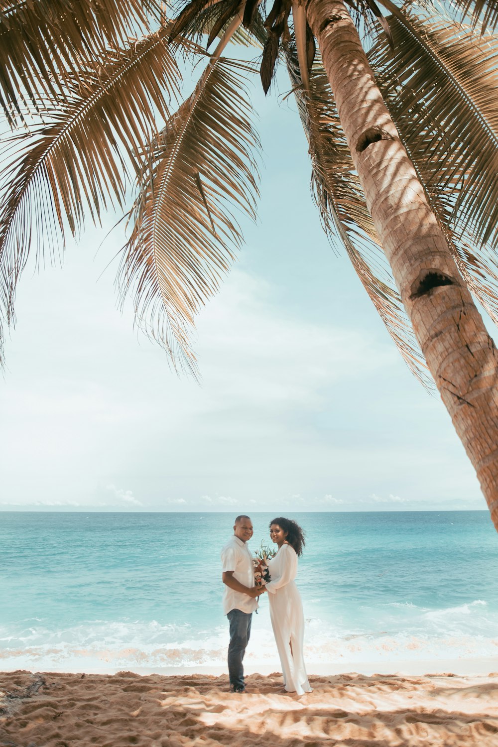 woman in white tank top sitting on palm tree during daytime