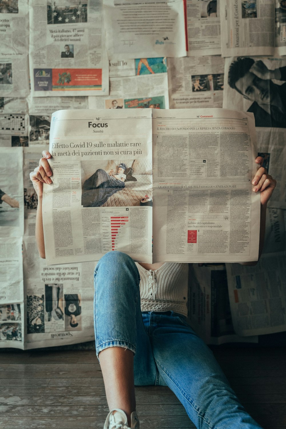 person in blue denim jeans holding white magazine