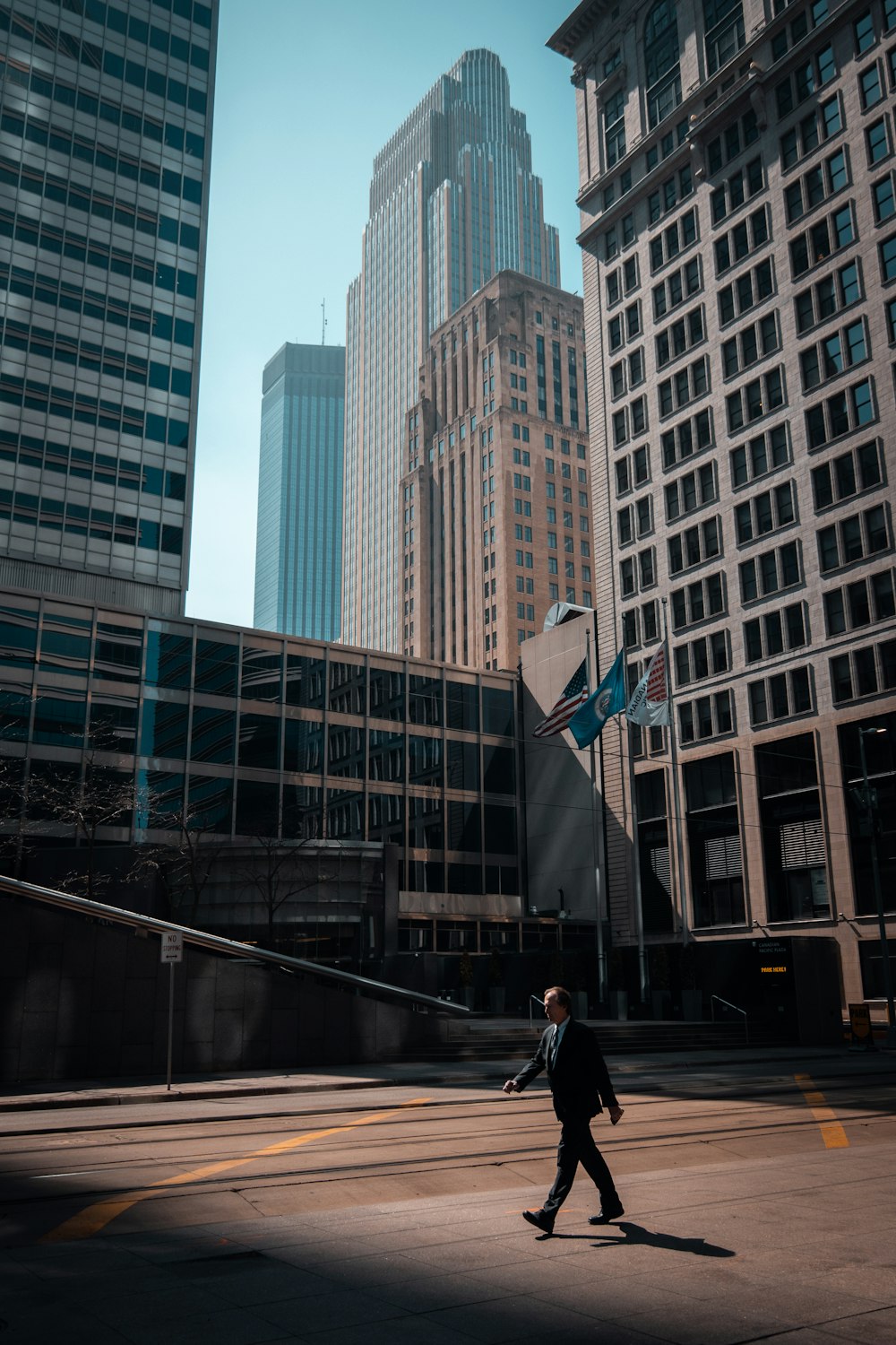 Mann in schwarzer Jacke geht tagsüber auf dem Bürgersteig in der Nähe des Gebäudes spazieren