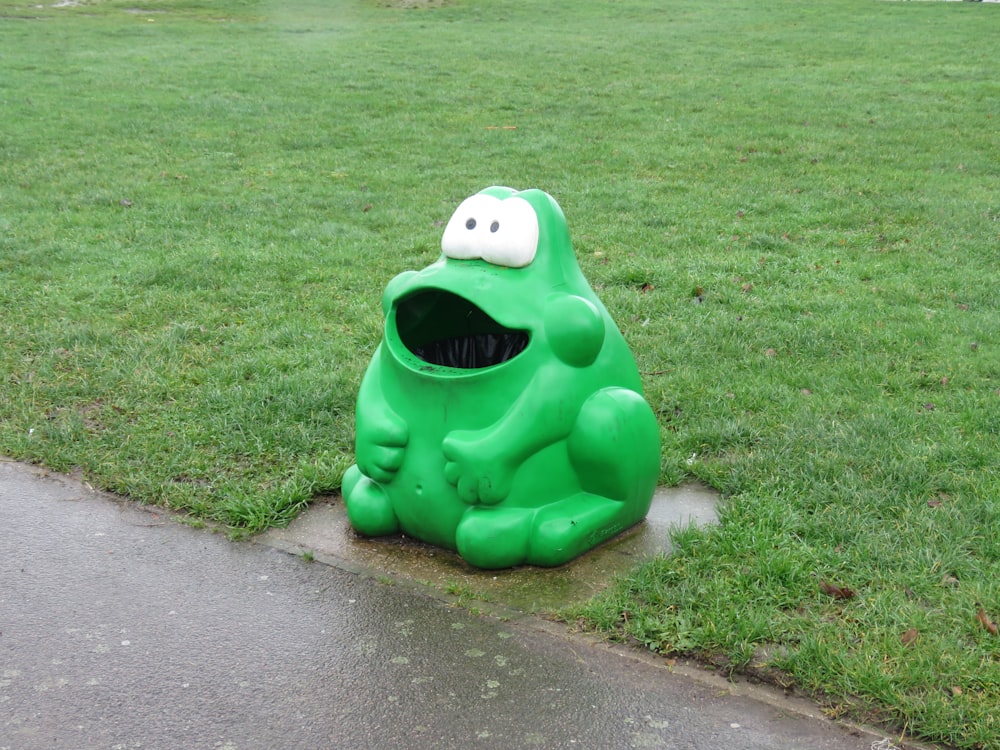 Statue de grenouille verte sur le champ d’herbe verte