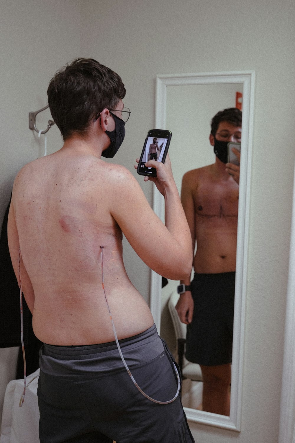 topless man in black shorts holding smartphone