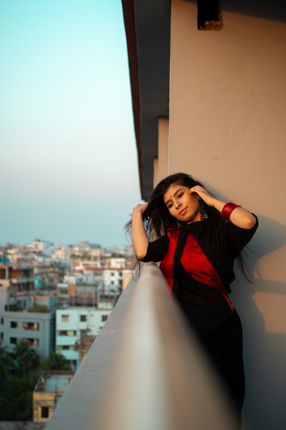 woman in black and red long sleeve shirt leaning on white wall during daytime