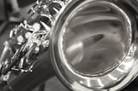 Artistic shot of saxophone keys shining under soft white light with mandala shadows around.