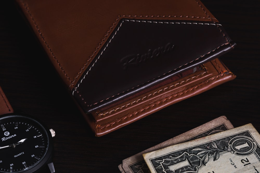 brown leather bifold wallet on black and white textile