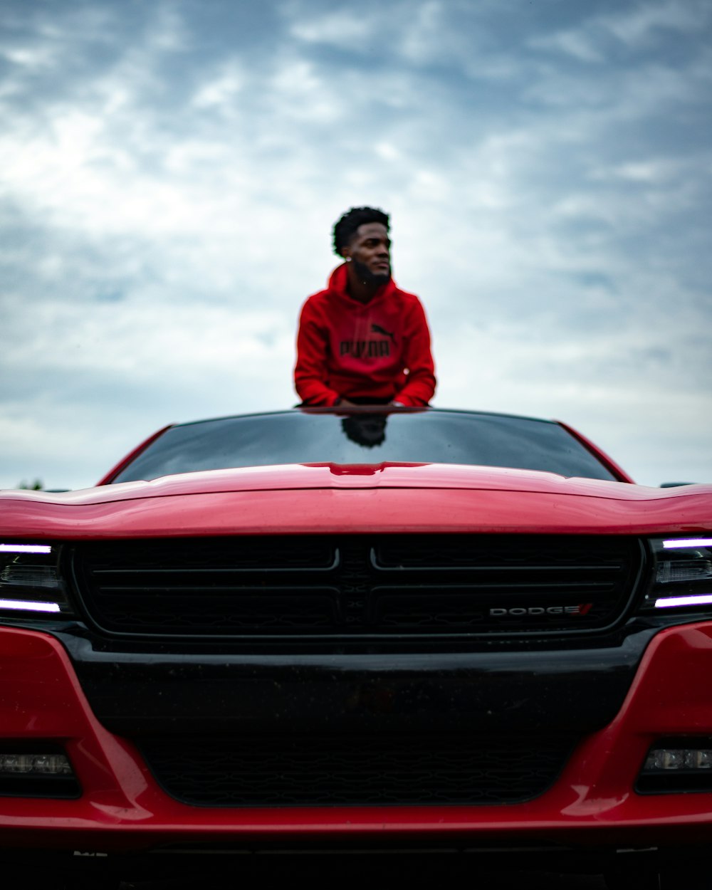 man in red jacket sitting on red chevrolet car
