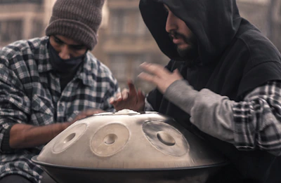 Close-up of hands gently striking a handpan in a cozy studio.