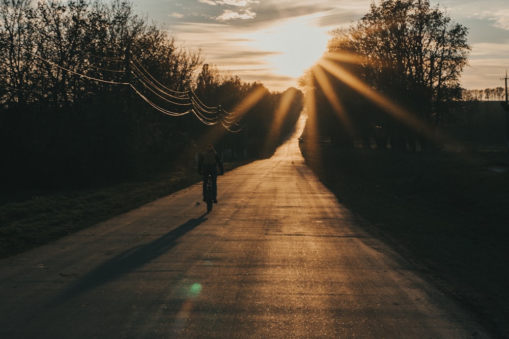 silhouette of person walking on road during sunset