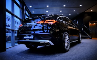 A sleek black luxury SUV parked in a modern showroom with golden accents.