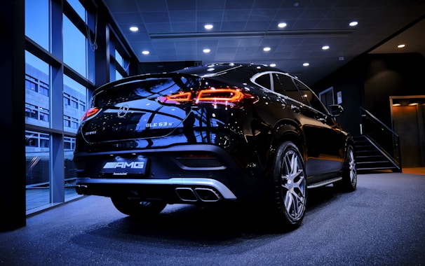A sleek black luxury SUV parked in a modern showroom with golden accents.