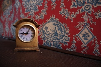 A vintage clock with ornate hands frozen in time, surrounded by aged wallpaper.