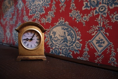 A close-up of a stylish wall clock with intricate details, set against a modern living room backdrop.