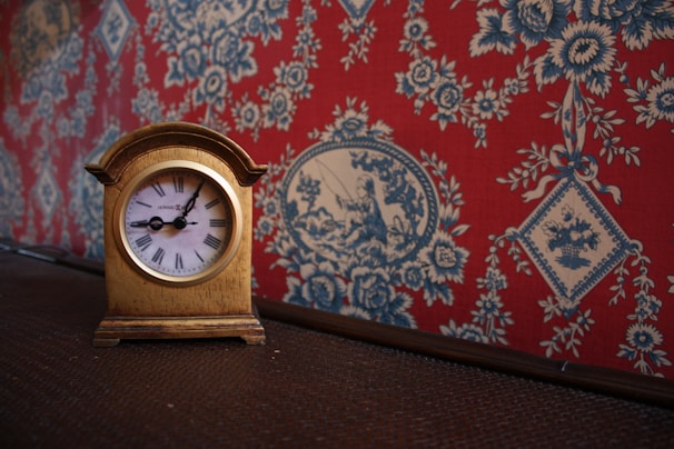 A vintage clock with ornate hands frozen in time, surrounded by aged wallpaper.
